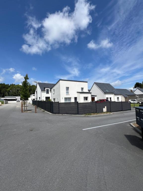 une rangée de maisons blanches avec une clôture noire dans l'établissement Le coteau du verger, à Sulniac