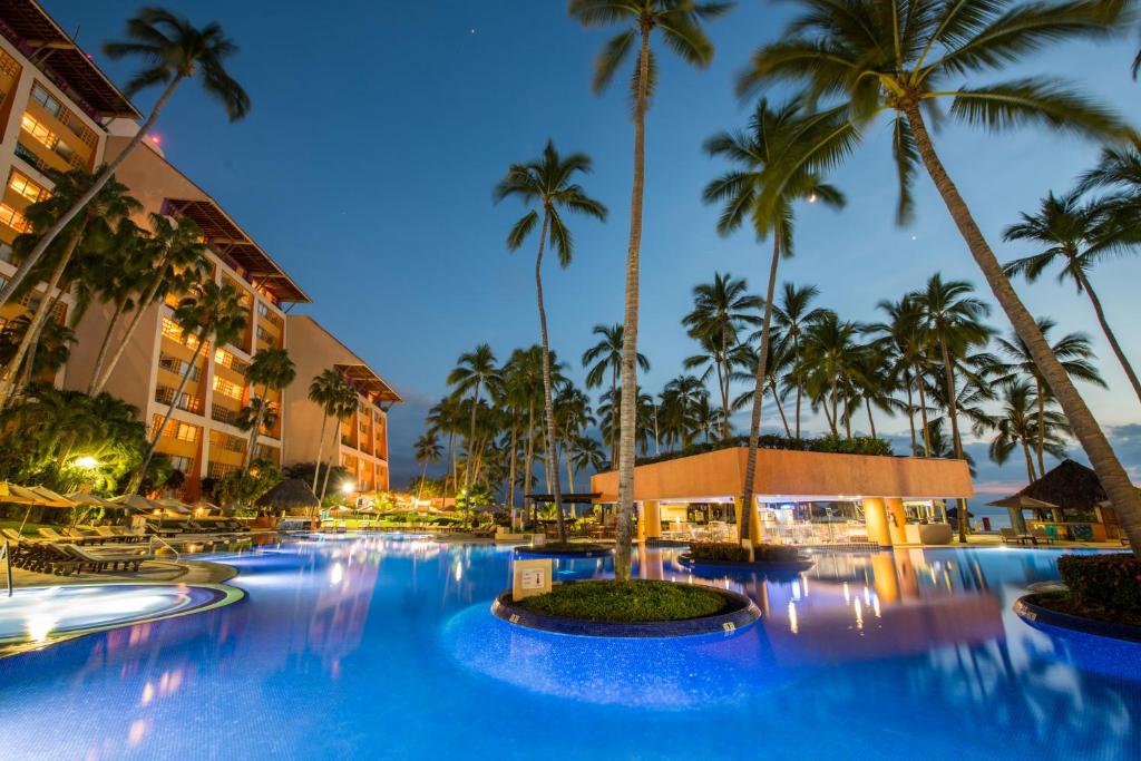a large pool with palm trees in front of a hotel at Club Regina Puerto Vallarta in Puerto Vallarta