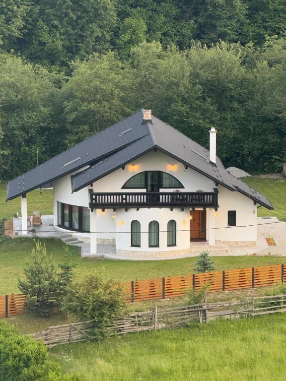 una gran casa blanca con techo negro en Julien House, en Prisaca Dornei