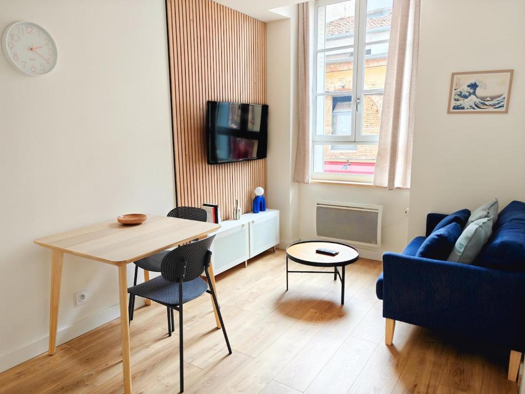 un salon avec une table et un canapé bleu dans l'établissement Jean Jaurès - 2 pièces au pied du métro, à Toulouse