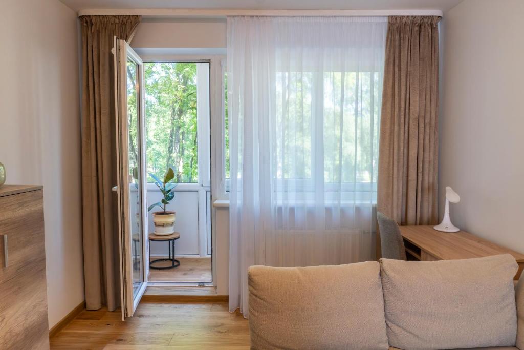 un soggiorno con un divano e una grande finestra di Saulės laikrodžio apartamentai a Šiauliai