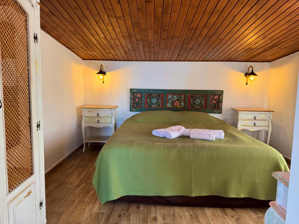 a bedroom with a green bed with two towels on it at Pangea Sığacık Suite Hotel & Bistro in Seferihisar