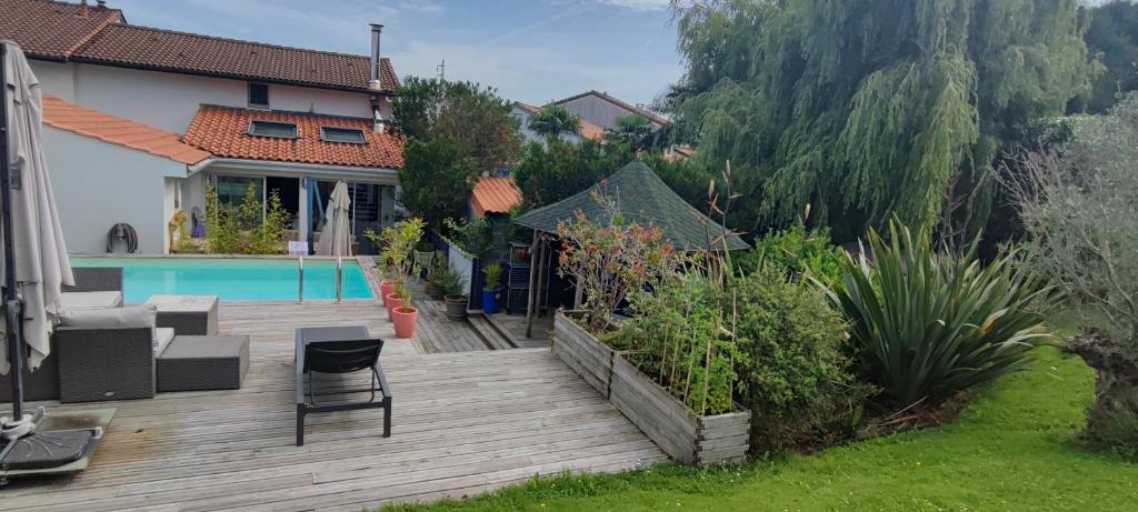 a house with a wooden deck next to a swimming pool at maison Saint Jean de Luz 6 personnes piscine et jacuzzi in Saint-Jean-de-Luz