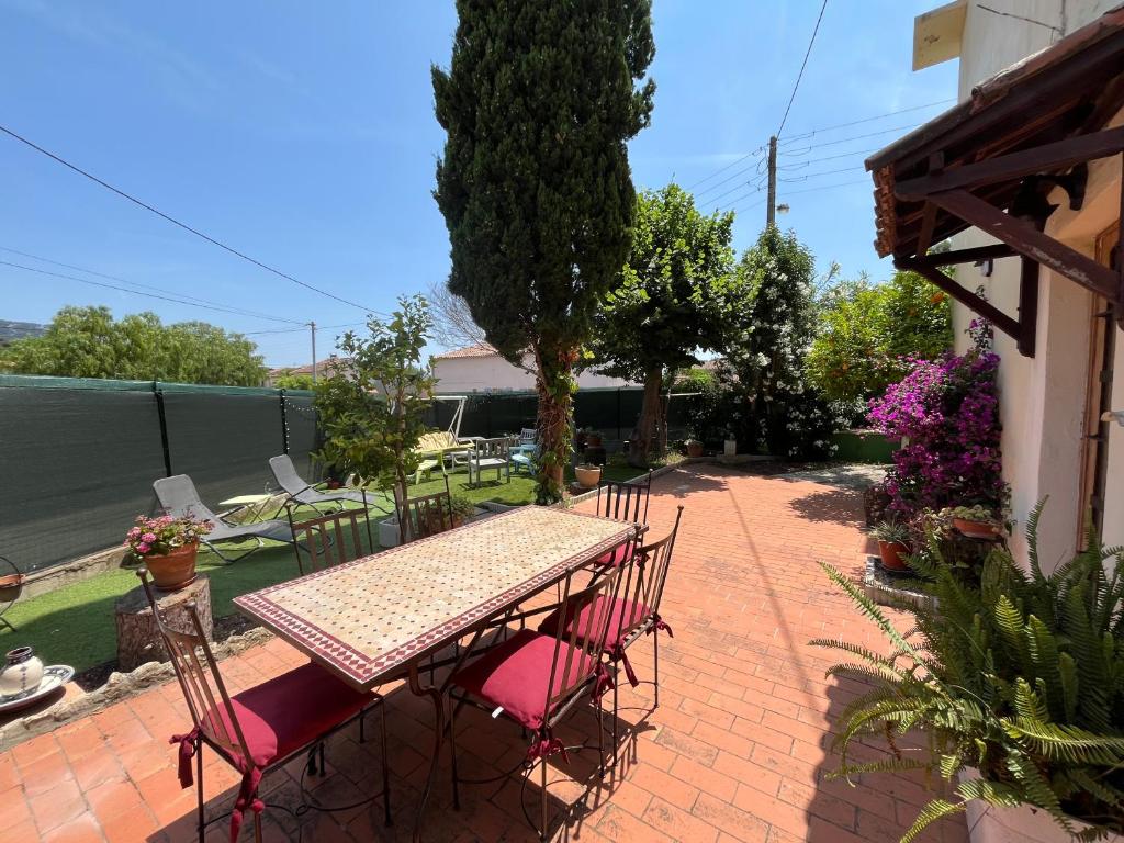 - une table de pique-nique et des chaises sur une terrasse en briques dans l'établissement Perle rare, F4 donnant sur un grand jardin privé aménagé, parkings gratuits, clim, calme, idéal famille & pro, 10 min de la mer et du centre-ville, de la gare sncf et routière, à Toulon