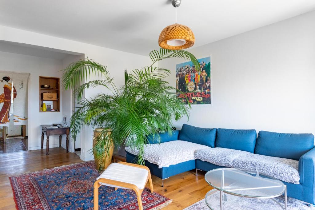 un canapé bleu dans un salon avec une plante dans l'établissement Spacieux appartement au calme proche de la mer, à Toulon
