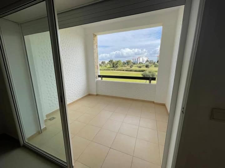 an empty room with a glass door and a window at Bel appartement avec piscine vue mer & golf in Asilah