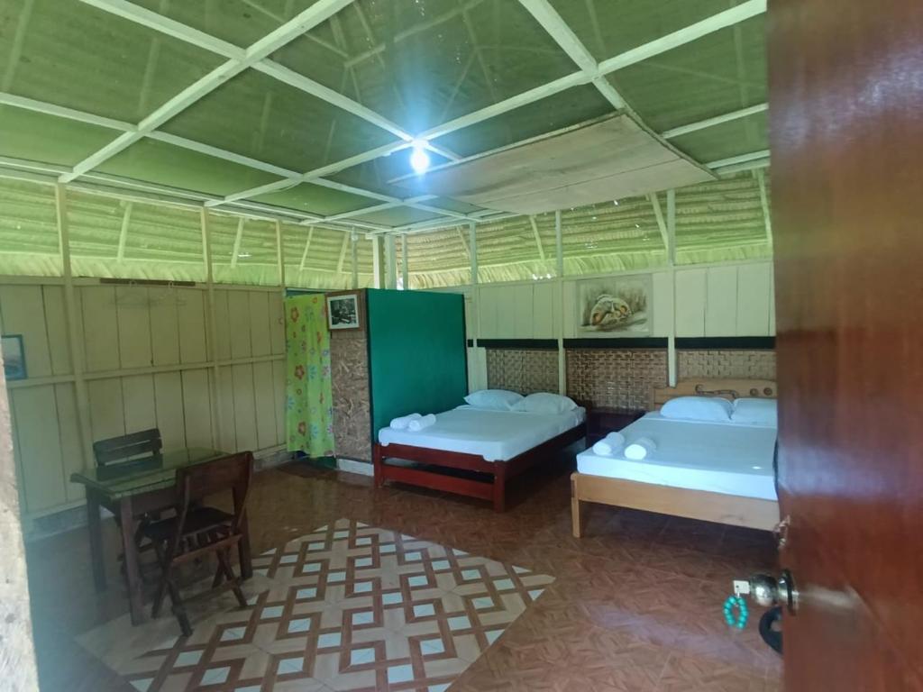 a room with two beds and a table in it at Resort&healing Center la tanrilla in Iquitos