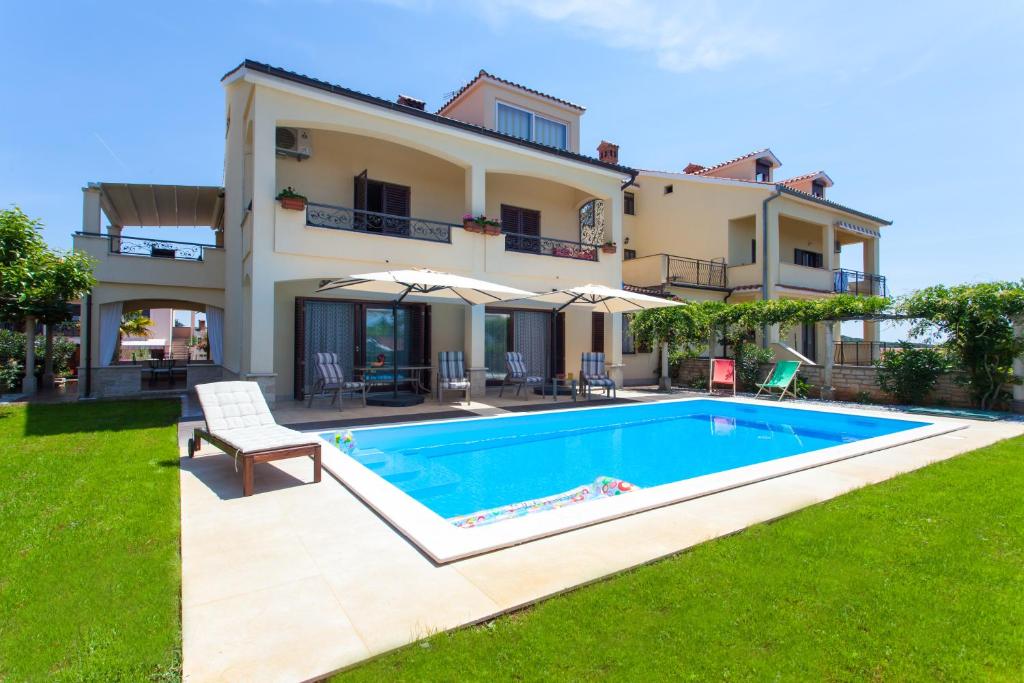 a villa with a swimming pool in front of a house at Premium Central Apartments in Vrsar
