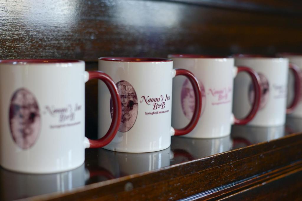 una fila de tazas de café sentadas en un estante en Naomi's Inn Bed & Breakfast, en Springfield
