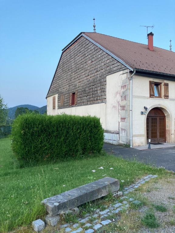 un bâtiment blanc avec une porte et une pelouse dans l'établissement Appartement indépendant dans jolie ferme vosgienne 1814 rénovée, à Remiremont