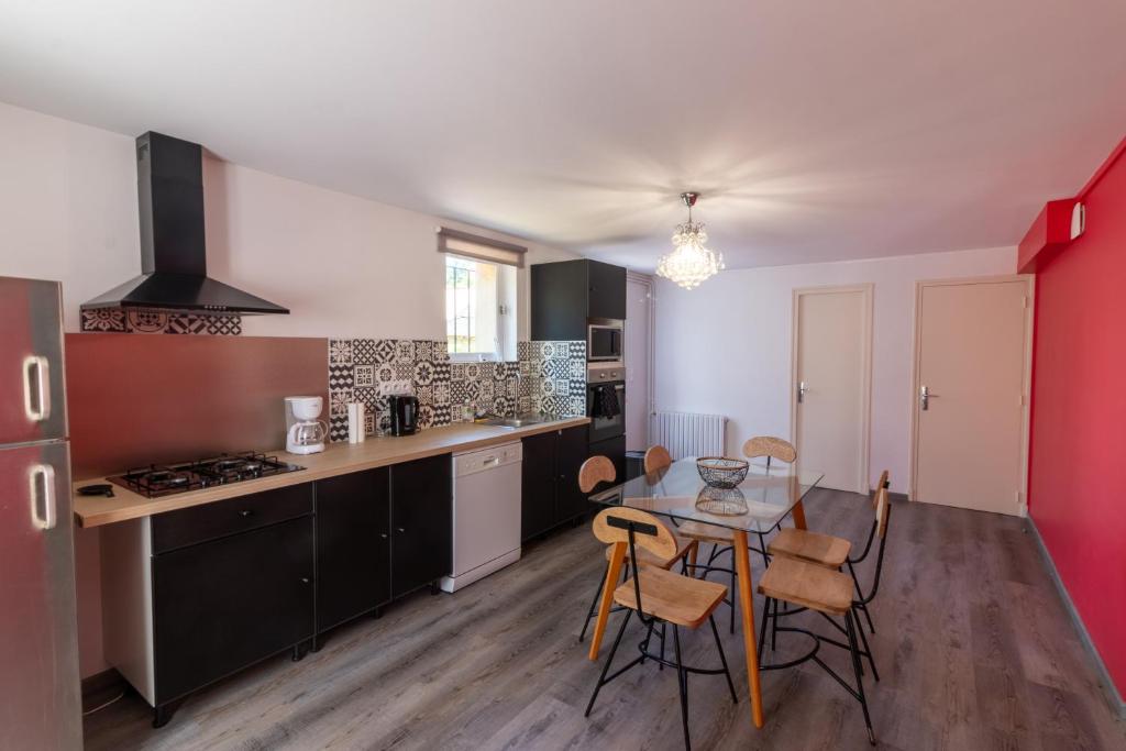 une cuisine avec une table et des chaises dans une pièce dans l'établissement Entre 2 Jardin Drap compris et Barbecue, à Sarlat-la-Canéda