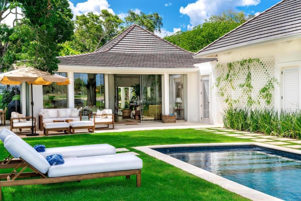 Un patio trasero con piscina y una casa. en Casa del Lago, en La Romana