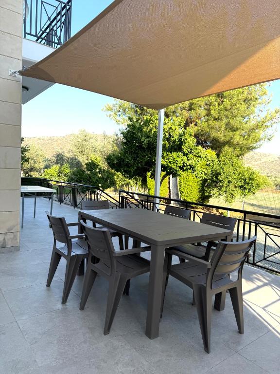 - une table et des chaises sous un parasol sur la terrasse dans l'établissement Himonas Apartments, à Pissoúri
