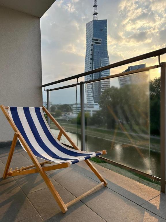 a chair on a balcony with a view of a city at Kapart Rzeszów Apartment in Rzeszów