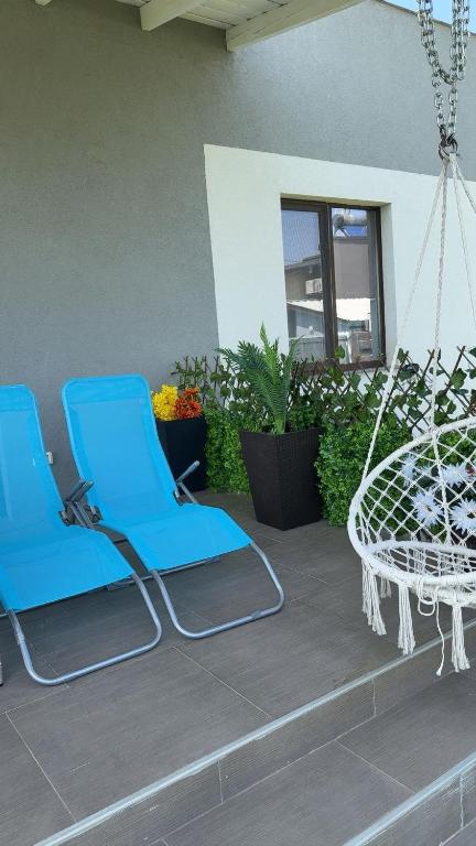 two blue chairs and a swing on a patio at Focsani Casa in Cîmpineanca