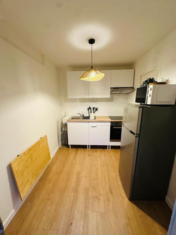 une cuisine avec un réfrigérateur et un plan de travail dans l'établissement Appartement tout neuf avec patio - 31, à Dax