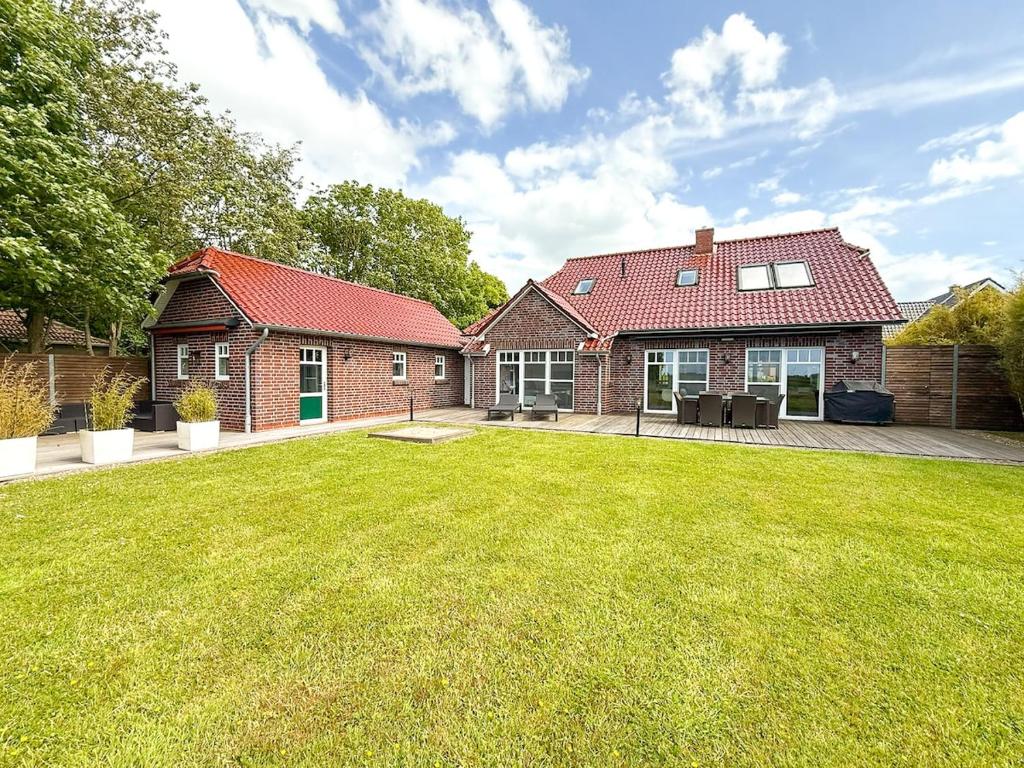 een stenen huis met een gazon ervoor bij Villa Neufunnixsiel in Neufunnixsiel