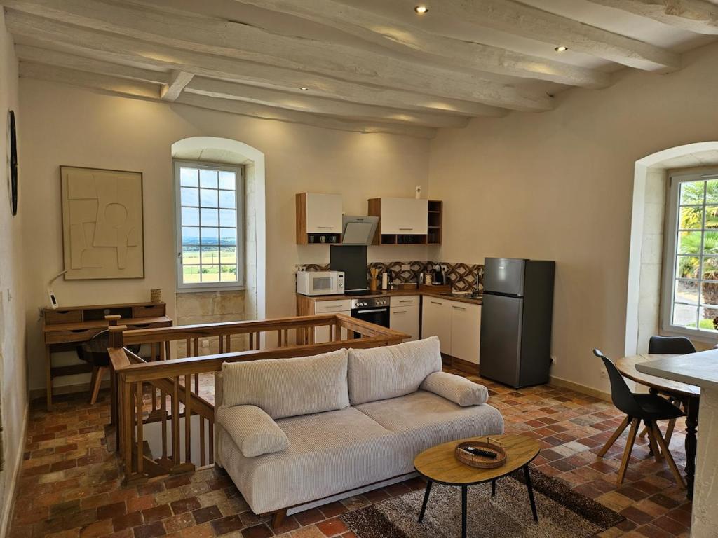 a living room with a couch and a kitchen at Cottage de la Plante in Thuré