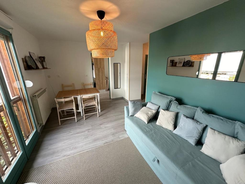 a living room with a blue couch and a table at Appartement rénové et lumineux - 130 in Dax