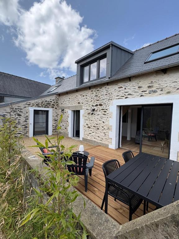 une maison dotée d'une terrasse en bois avec une table et des chaises dans l'établissement Maison en Pierre au calme, à Binic
