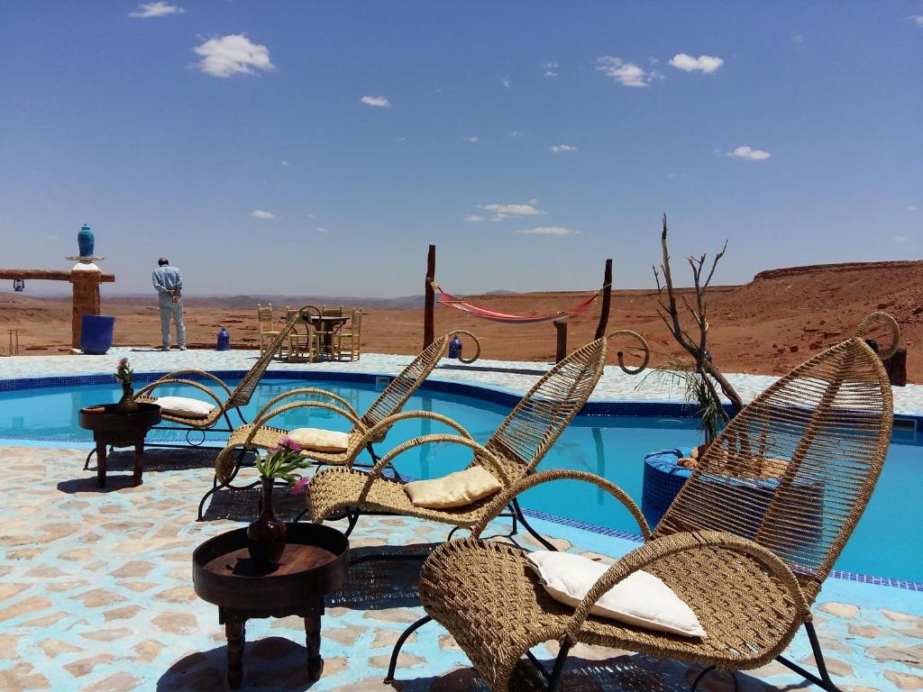 a beach area with chairs, tables, chairs and umbrellas at Riad Paradise of Silence in Aït Benhaddou