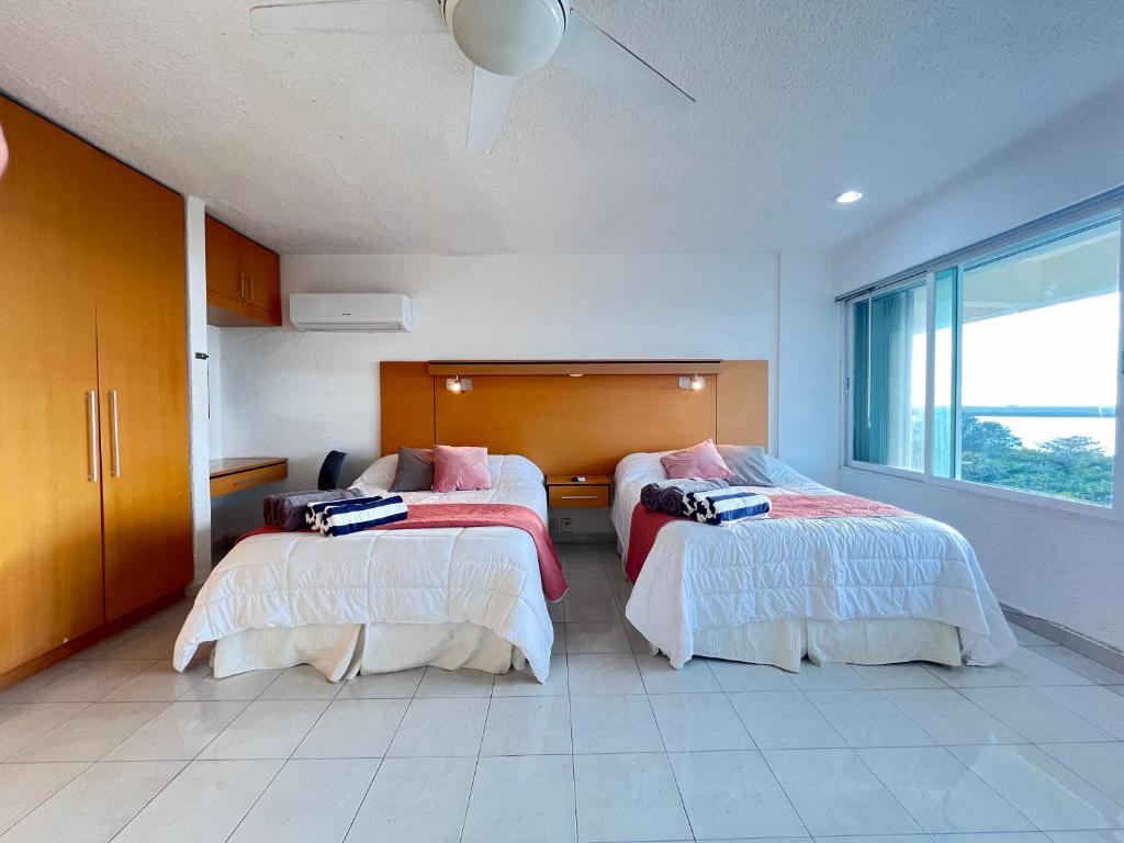 a bedroom with two beds and a large window at Comoda Suite Cancun - BEACH CONDO - 6PX in Cancún