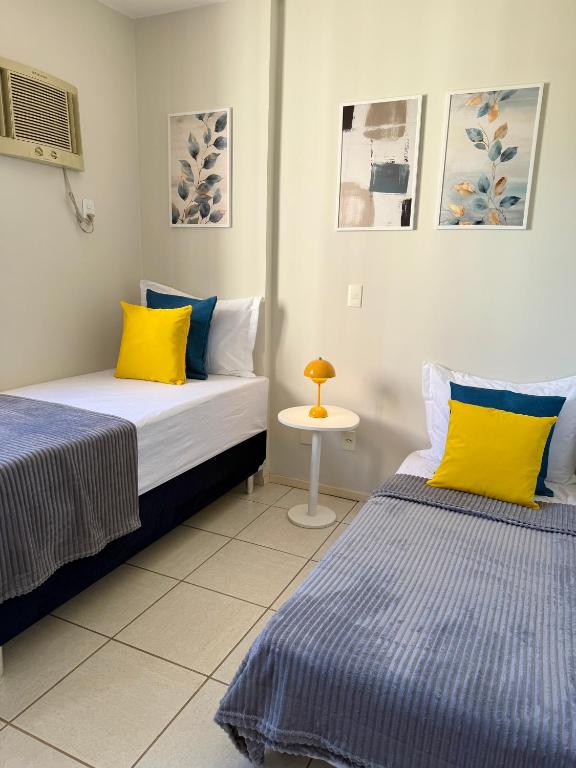 two beds with yellow and blue pillows in a room at Melhor Experiência em Cuiabá in Cuiabá