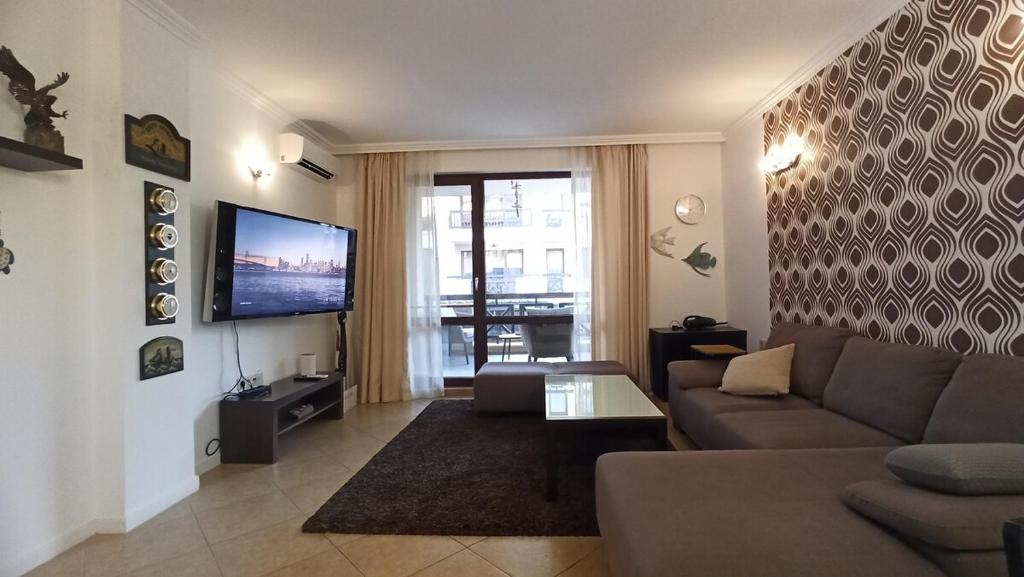 a living room with a couch and a flat screen tv at Premium Oasis Beach Club Apartment in Lozenets
