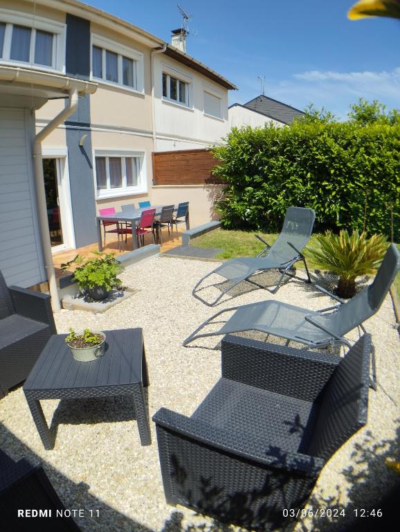 un patio avec des chaises et des tables et un bâtiment dans l'établissement Maison à 5' du circuit du Mans, à Mulsanne