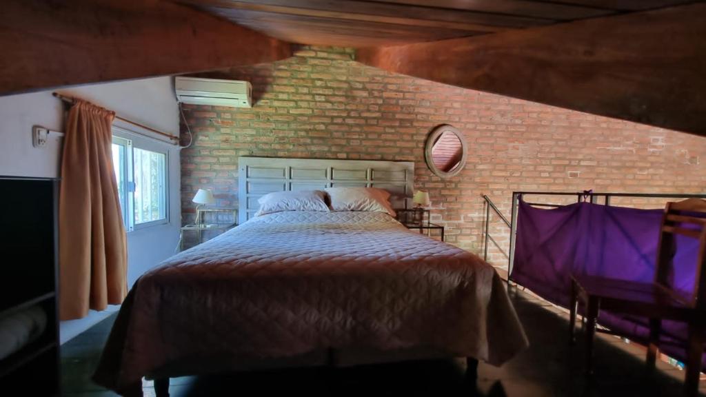 Un dormitorio con una cama y una pared de ladrillo. en Las Calandrias, en Funes
