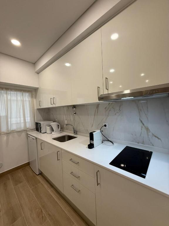 Una cocina con gabinetes blancos y un fregadero. en Casa Rabiosa, en Nazaré