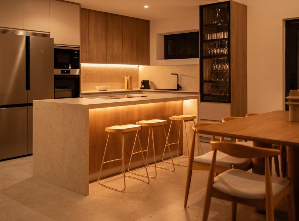 a kitchen with a counter and chairs and a refrigerator at Villa Sancti Petri, entre el golf y la playa in Novo Sancti Petri