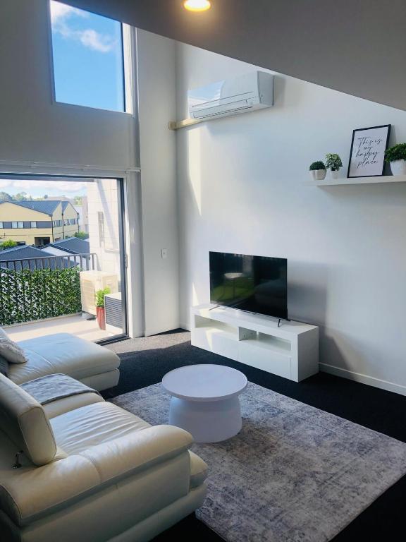 a living room with a couch and a flat screen tv at Modern minimalistic apartment,3BR in Auckland