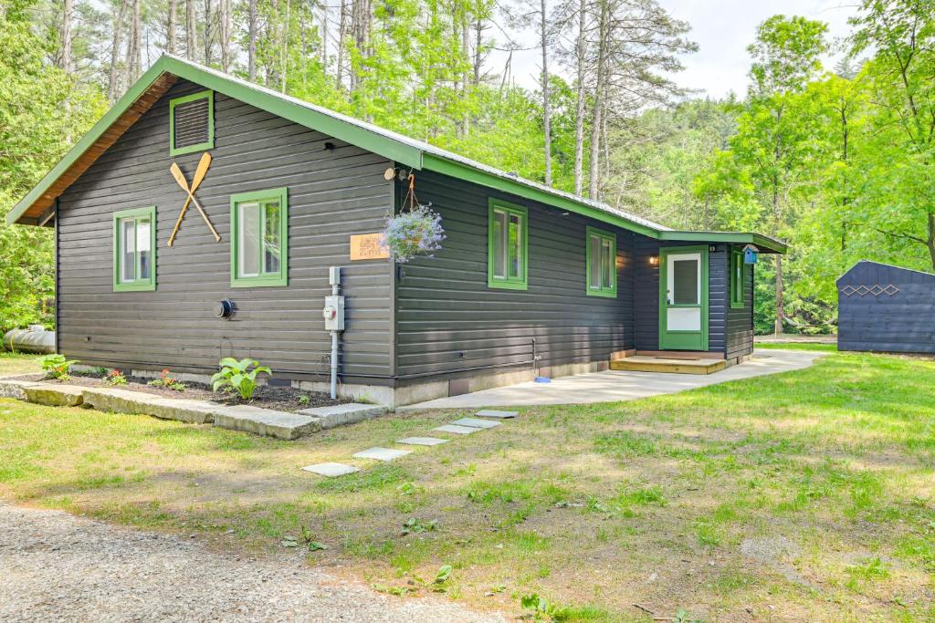 a cabin in the woods with a green door at Riverfront Cabin w/ Hot Tub in Schroon Lake! in Schroon Lake