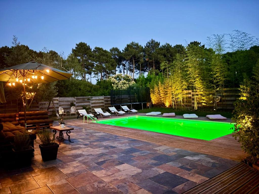 une cour arrière avec une piscine verte dans la cour dans l'établissement Seawest avec piscine à 5 min de l'océan, à Vielle-Saint-Girons