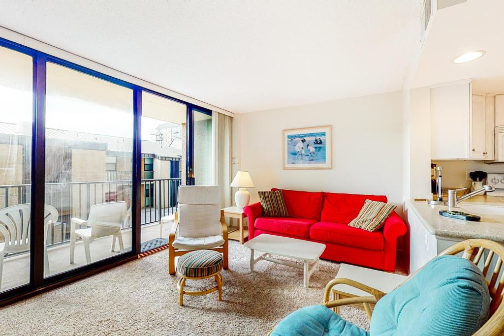 a living room with a red couch and a kitchen at Sea Colony - 203 Brandywine House Rd in Bethany Beach