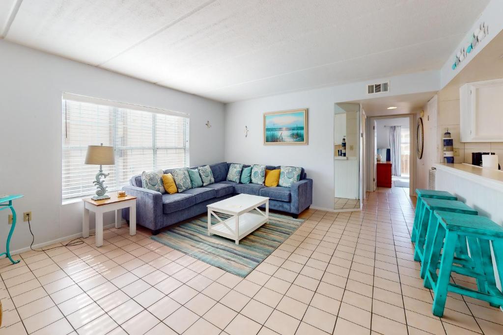 a living room with a blue couch and a table at Fiesta Sol Condominiums #109 in South Padre Island