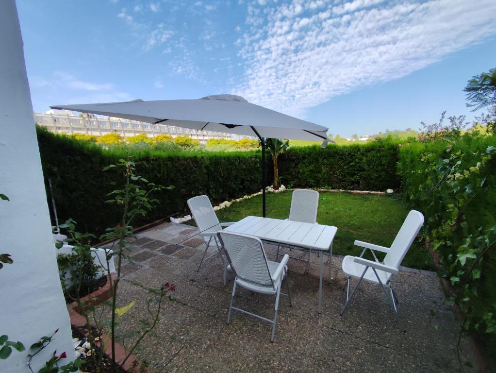 a table and chairs under an umbrella in a garden at Del jardín a la playa in Islantilla