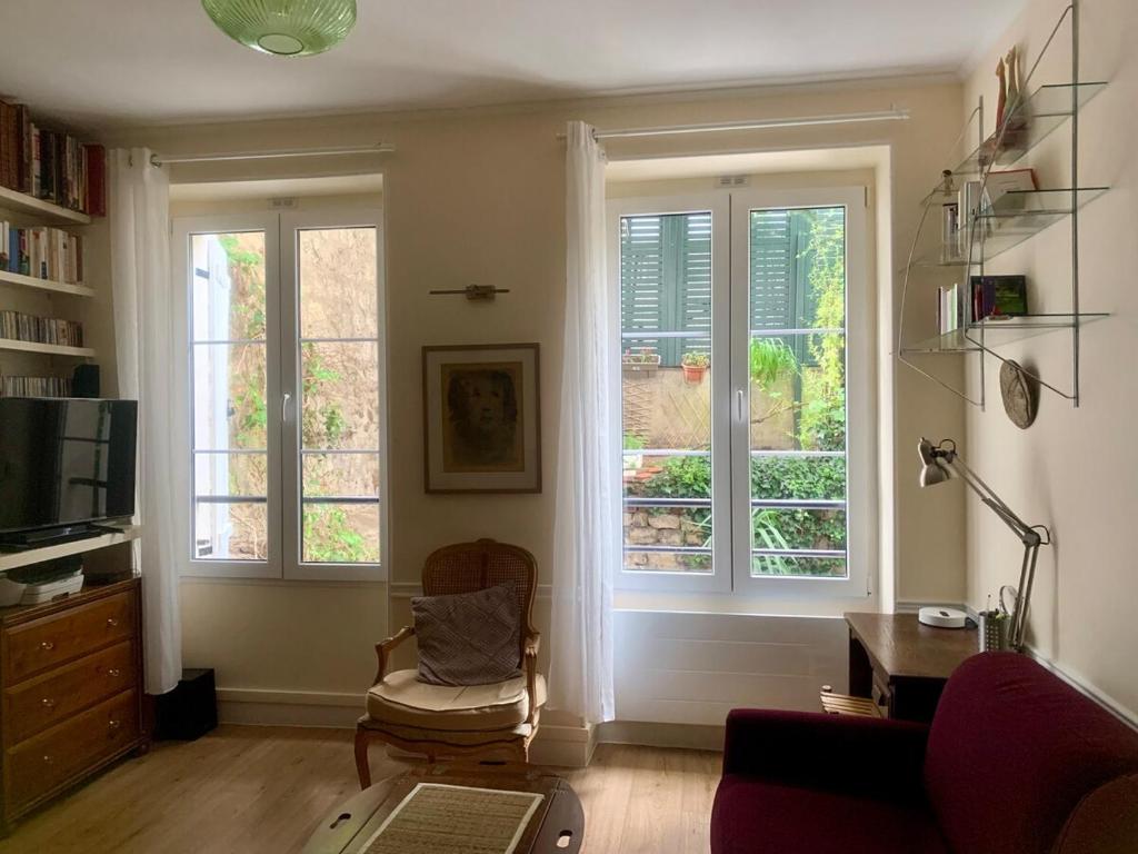 - un salon avec deux fenêtres et une chaise dans l'établissement Buffon CI- Charming apartment with gardens of plants, à Paris