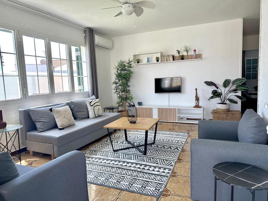 a living room with blue couches and a tv at Chalets con piscinas privadas junto al mar in Cala'n Bosch