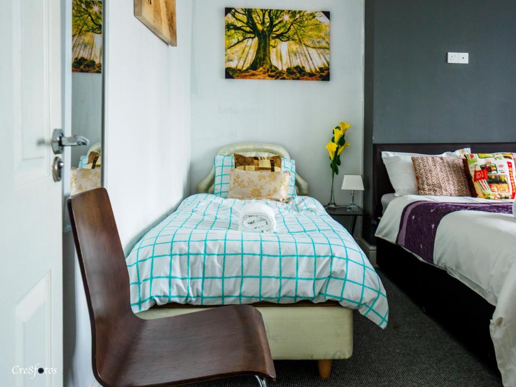 a small bedroom with a bed and a chair at Bucknall Lodge Hanley Family Room 1 in Stoke on Trent
