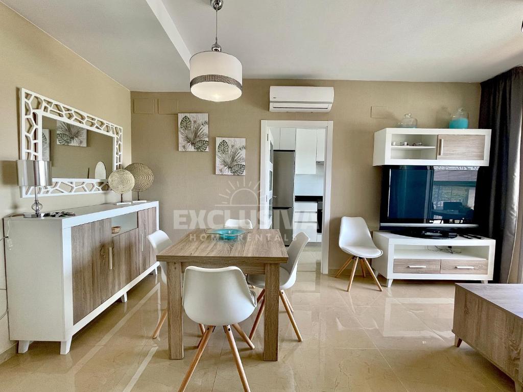 un salon avec une table et une télévision dans l'établissement Perla Home, 1ªLínea, Magic World, à El Borseral