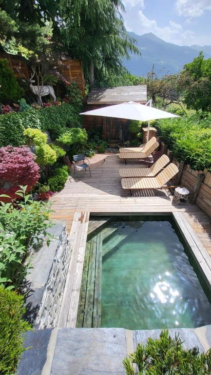 a swimming pool with chairs and an umbrella at La Bergerie du Miravidi in Bourg-Saint-Maurice