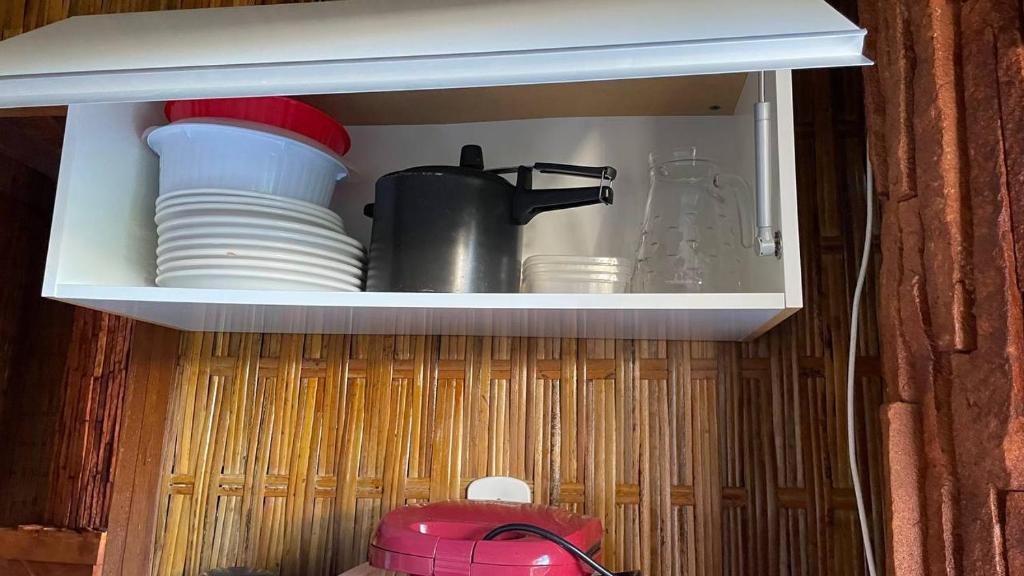 a cupboard with plates and a pot and dishes at Casa na orla in Porto Seguro