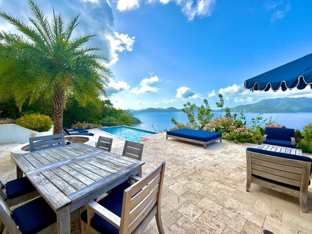 East EndにあるAmazing Views, Stunning Pool, Eco-Luxury Getaway - Dove Cottageのパティオ(木製のテーブルと椅子、プール付)