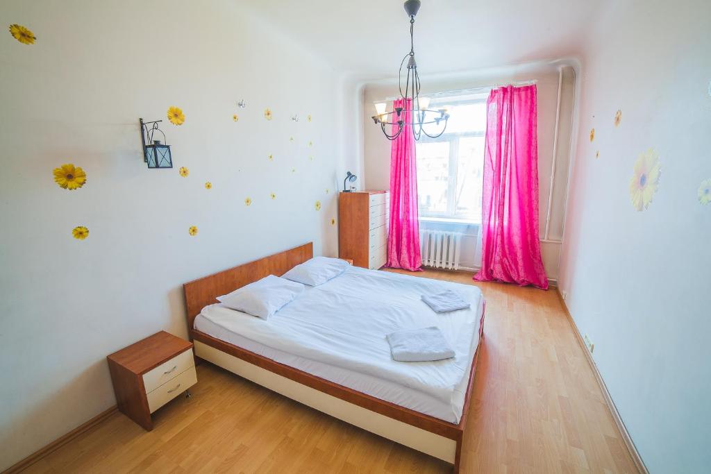 里加的住宿－Heart of Old-Town Apartments，一间卧室配有床和一个带粉红色窗帘的窗户。