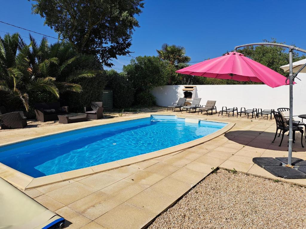 une piscine avec une table et un parasol dans l'établissement Maison confortable avec piscine privée, 3 chambres, proche forêt et plage. - FR-1-323-542, à Saint-Jean-de-Monts