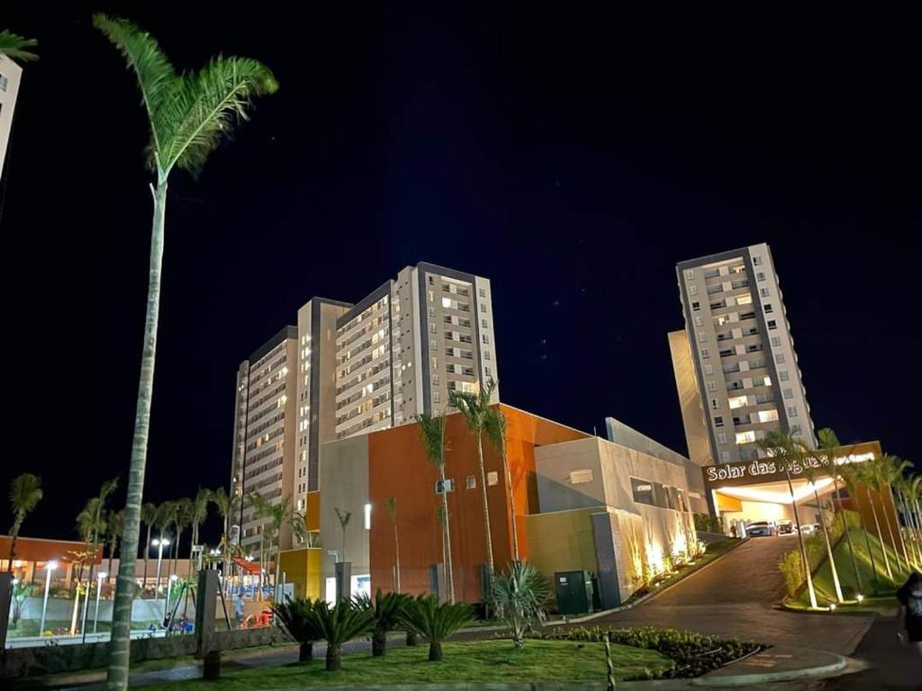 zwei hohe Gebäude in der Nacht mit einer Palme in der Unterkunft Solar das Águas Park Resort, Ap para Temporada in Olímpia