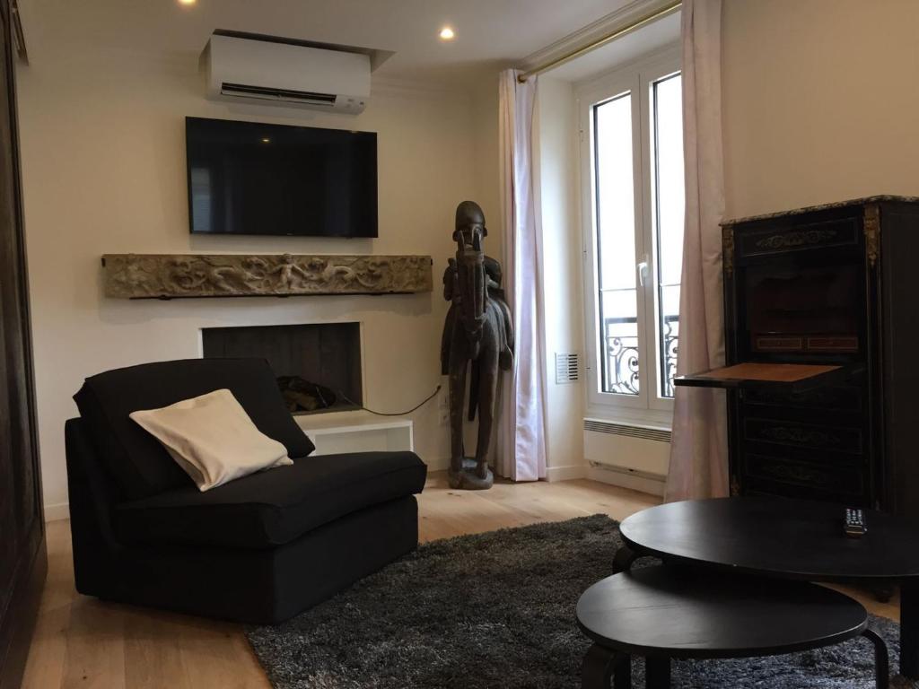 - un salon avec une chaise noire et une cheminée dans l'établissement Bellechasse Apartments, à Paris