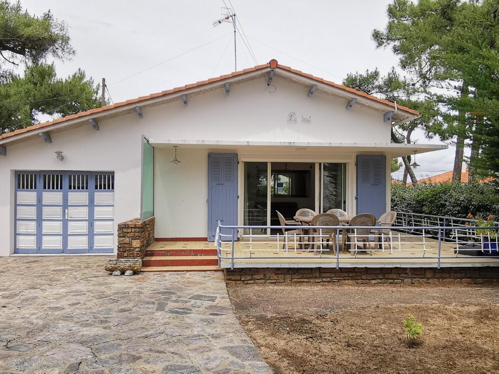 une petite maison blanche avec des chaises sur la terrasse couverte dans l'établissement Maison 3 chambres, 150 m de la plage, 4/6 pers, WI-FI, terrasse, parking, proche commerces, La Tranche sur Mer - FR-1-357-23, à La Tranche-sur-Mer